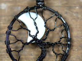 A mother of pearl crescent moon peeks out from behind the black wire branches of this handmade wire wrapped tree of life pendant like a lunar eclipse in the night sky.