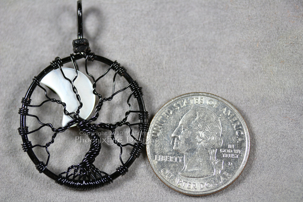 A mother of pearl crescent moon peeks out from behind the black wire branches of this handmade wire wrapped tree of life pendant like a lunar eclipse in the night sky.