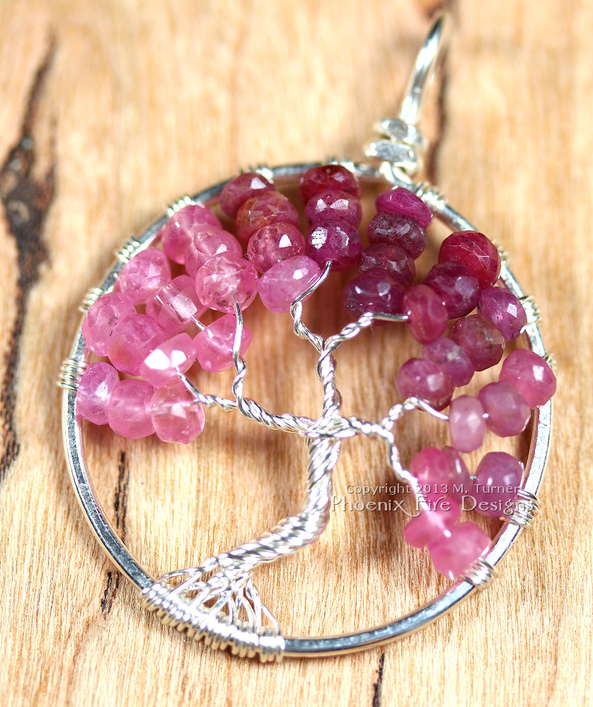 Stunning shaded ombre red, raspberry and pink ruby rondelles in silver wire make up this Tree of Life Pendant featuring July's precious gemstone birthstone.