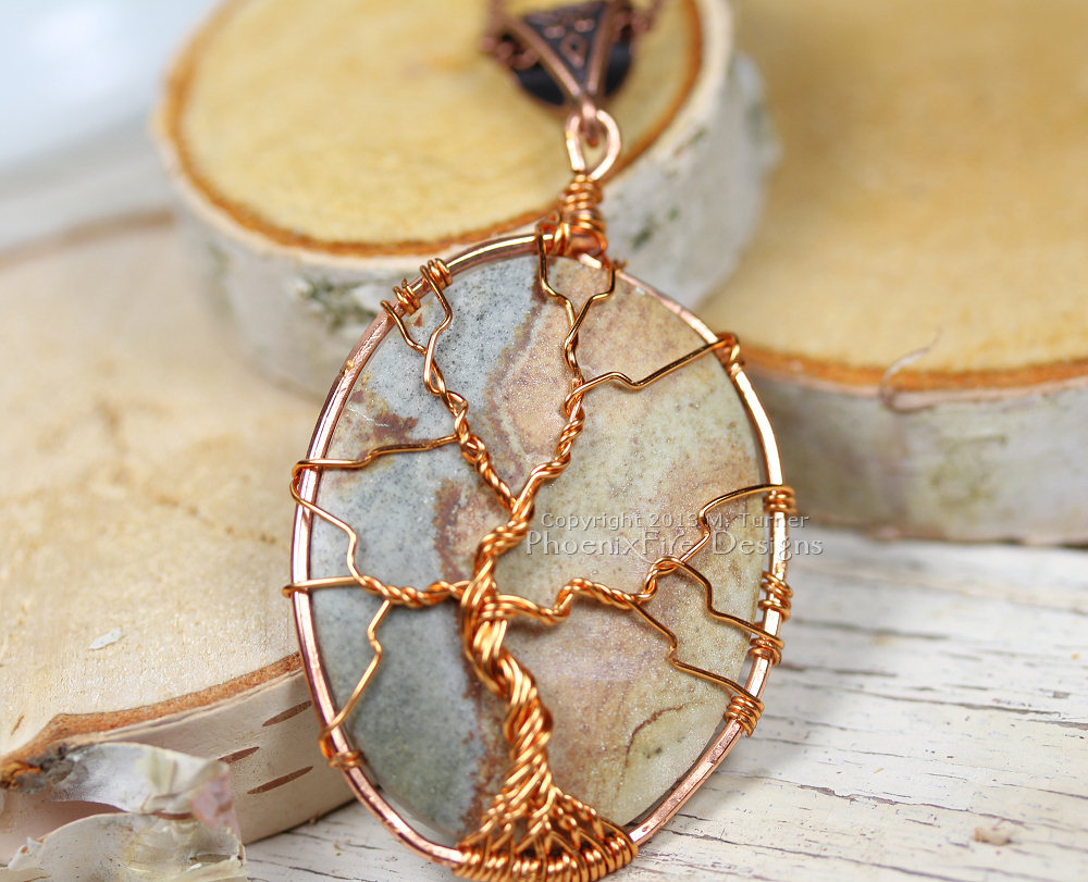 A multicolor cabochon agate is encircled in copper and a tree of life pendant is wire wrapped on the surface forming this beautiful, natural necklace. On 18" chain.