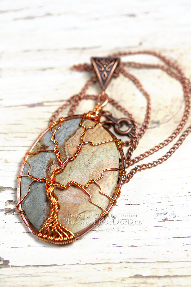 A multicolor cabochon agate is encircled in copper and a tree of life pendant is wire wrapped on the surface forming this beautiful, natural necklace. On 18" chain.