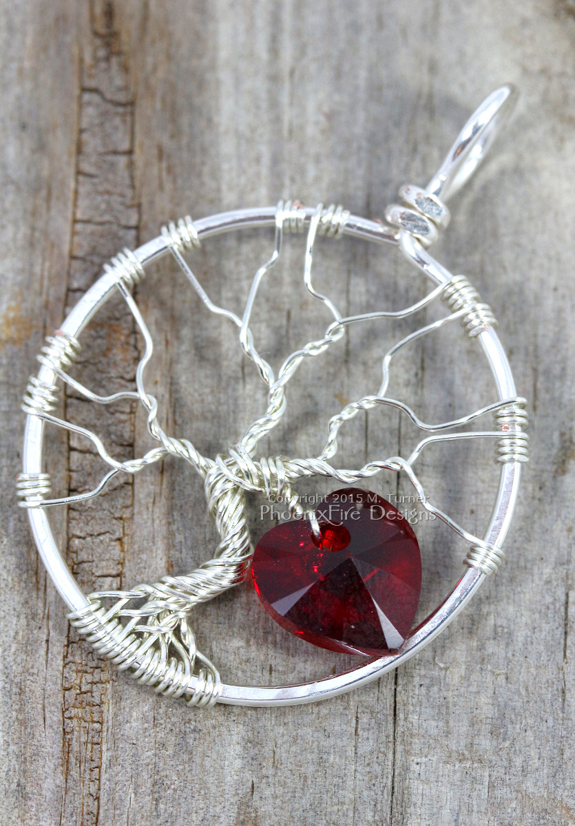 Handmade wire wrapped tree of life pendant with siam red Swarovski crystal heart dangling from the silver wire branches by Phoenix Fire Designs on etsy.
