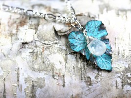 Glowing blue micro-faceted Rainbow Moonstone Briolette is nestled on a verdigris patina brass leaf charm. On a sterling silver plated chain of 18 inches.