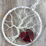 Handmade wire wrapped tree of life pendant with siam red Swarovski crystal heart dangling from the silver wire branches by Phoenix Fire Designs on etsy.