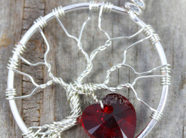 Handmade wire wrapped tree of life pendant with siam red Swarovski crystal heart dangling from the silver wire branches by Phoenix Fire Designs on etsy.